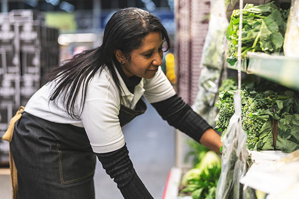 woman stocking produce at a supermarket